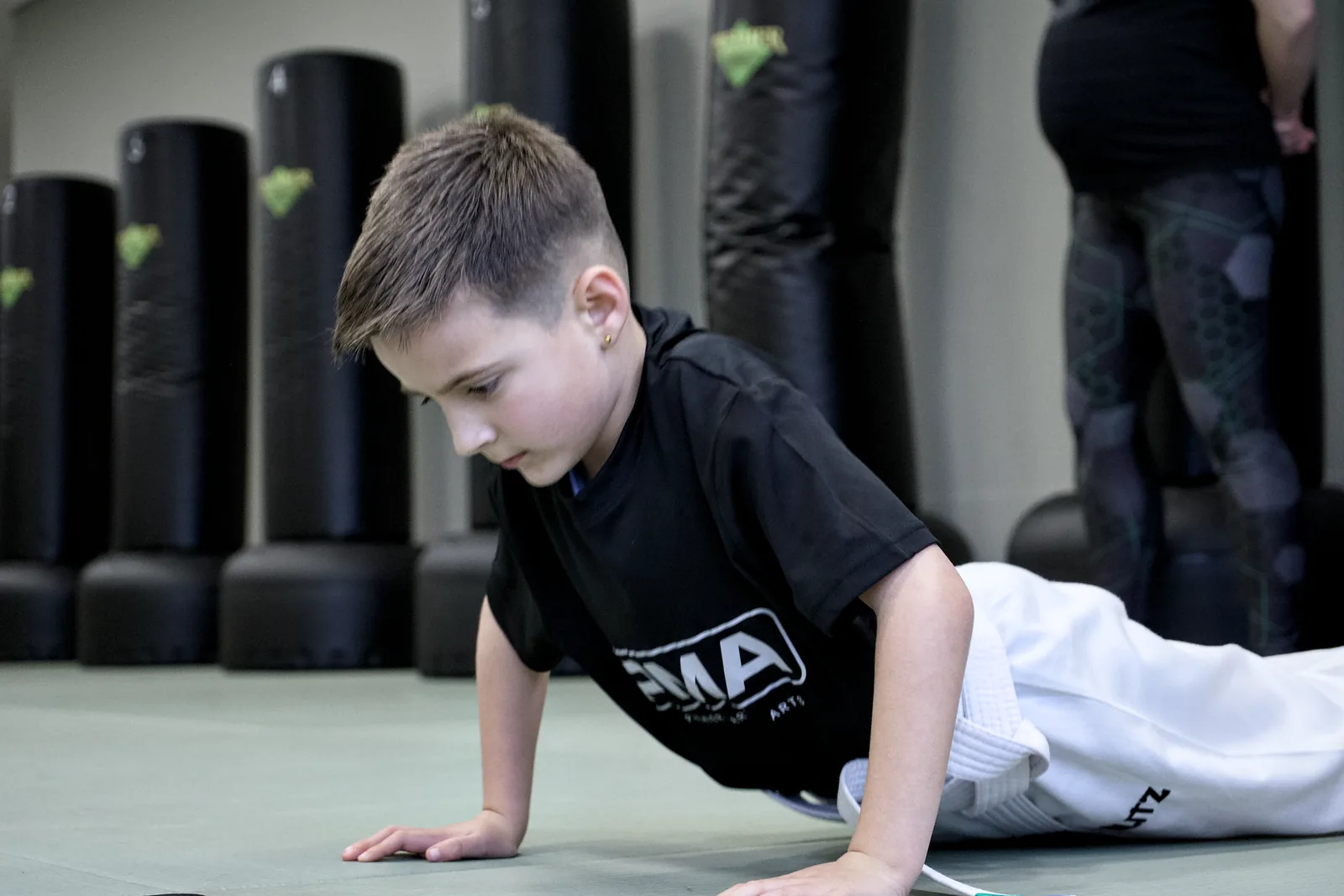 A young boy pressing up off the mat during a warm-up