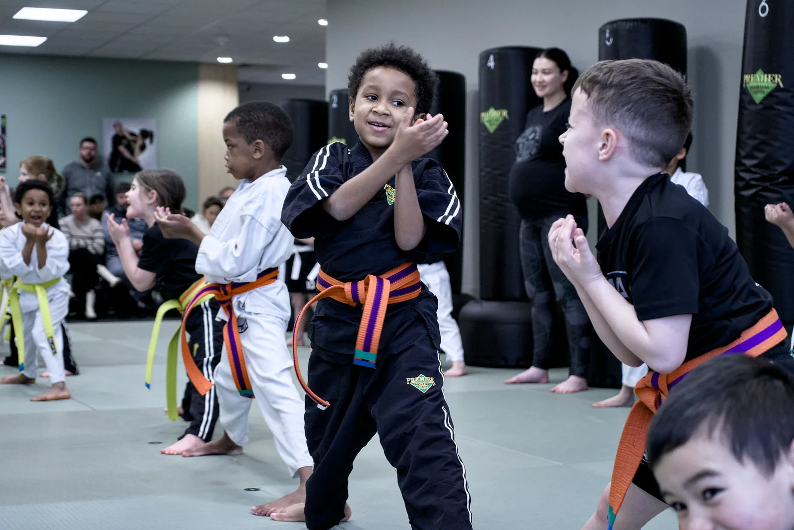 Two small children in coloured belts laughing together on the mat
