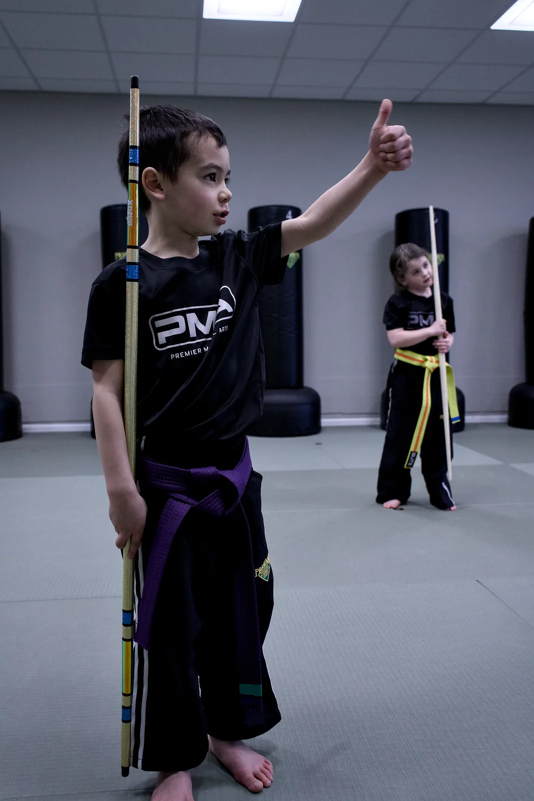 A young child with a hand raised, answering the instructor