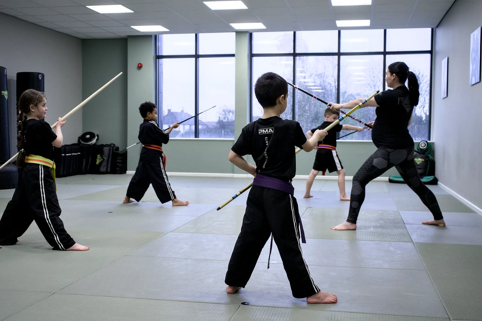 Two students working a weapons drill in the middle of an empty mat