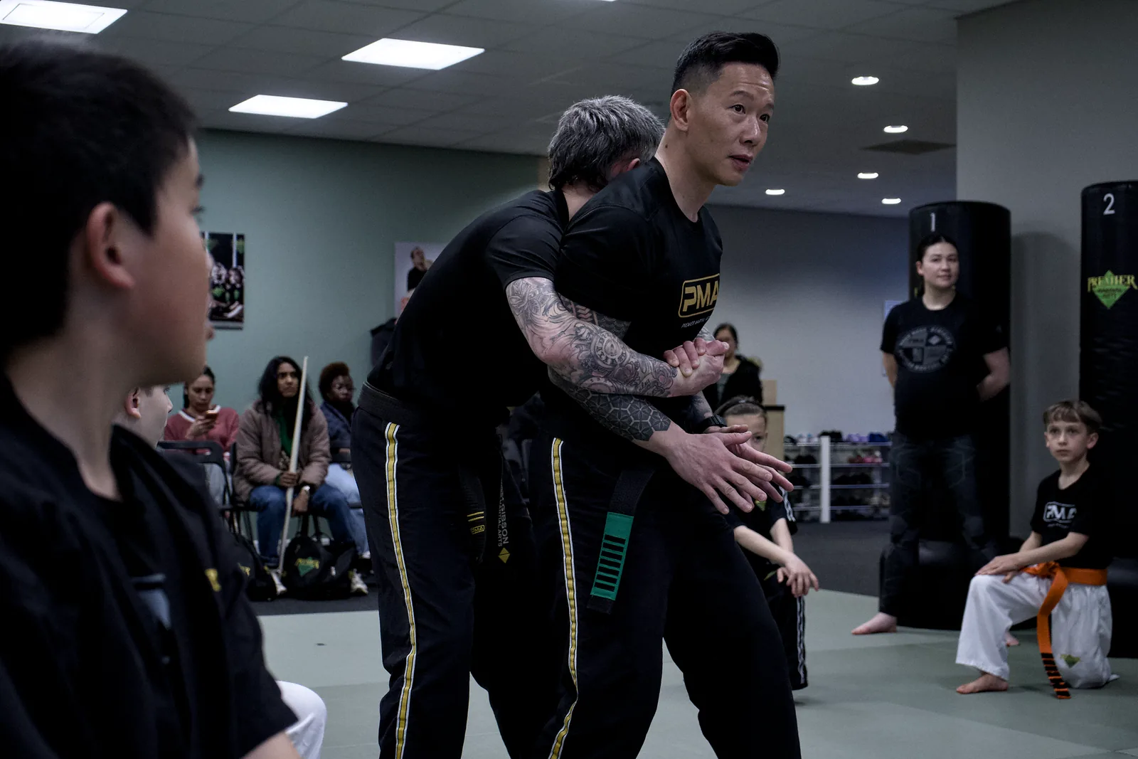 An instructor crouching to guide a small child through a stance