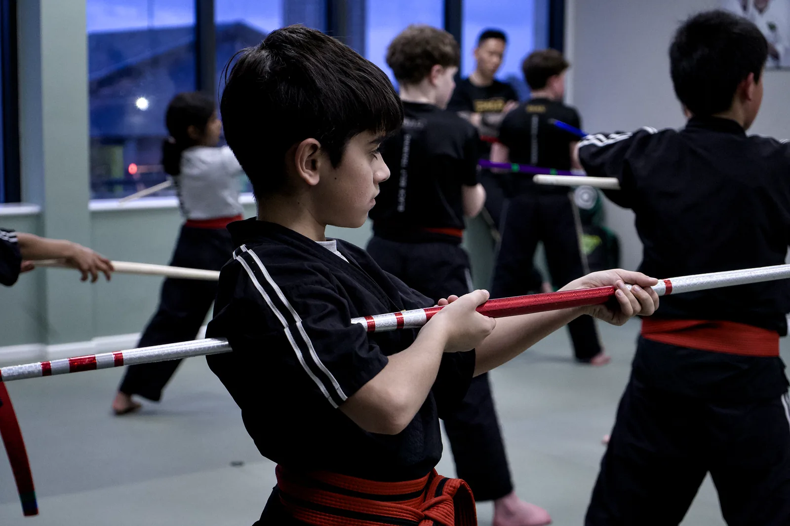 A boy holding a training staff across his body, ready to begin