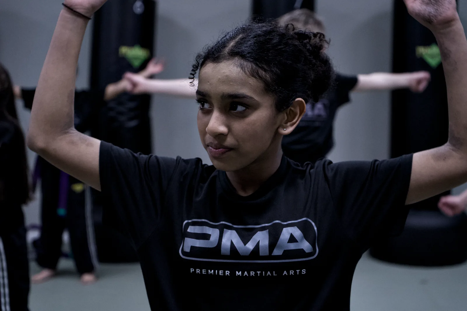 A girl in a PMA shirt holding a high guard, concentrating