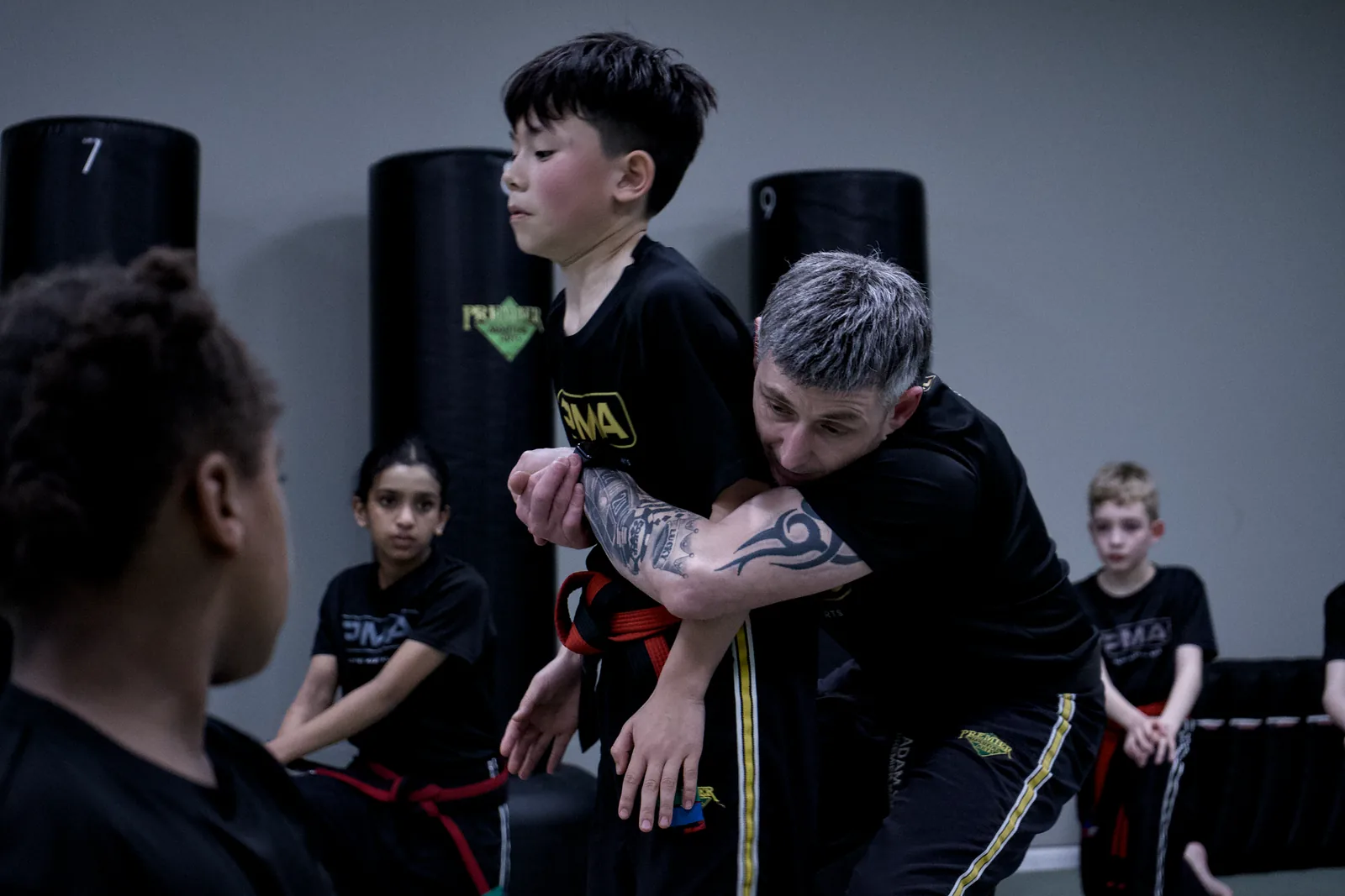 An instructor kneeling to correct a child's guard position