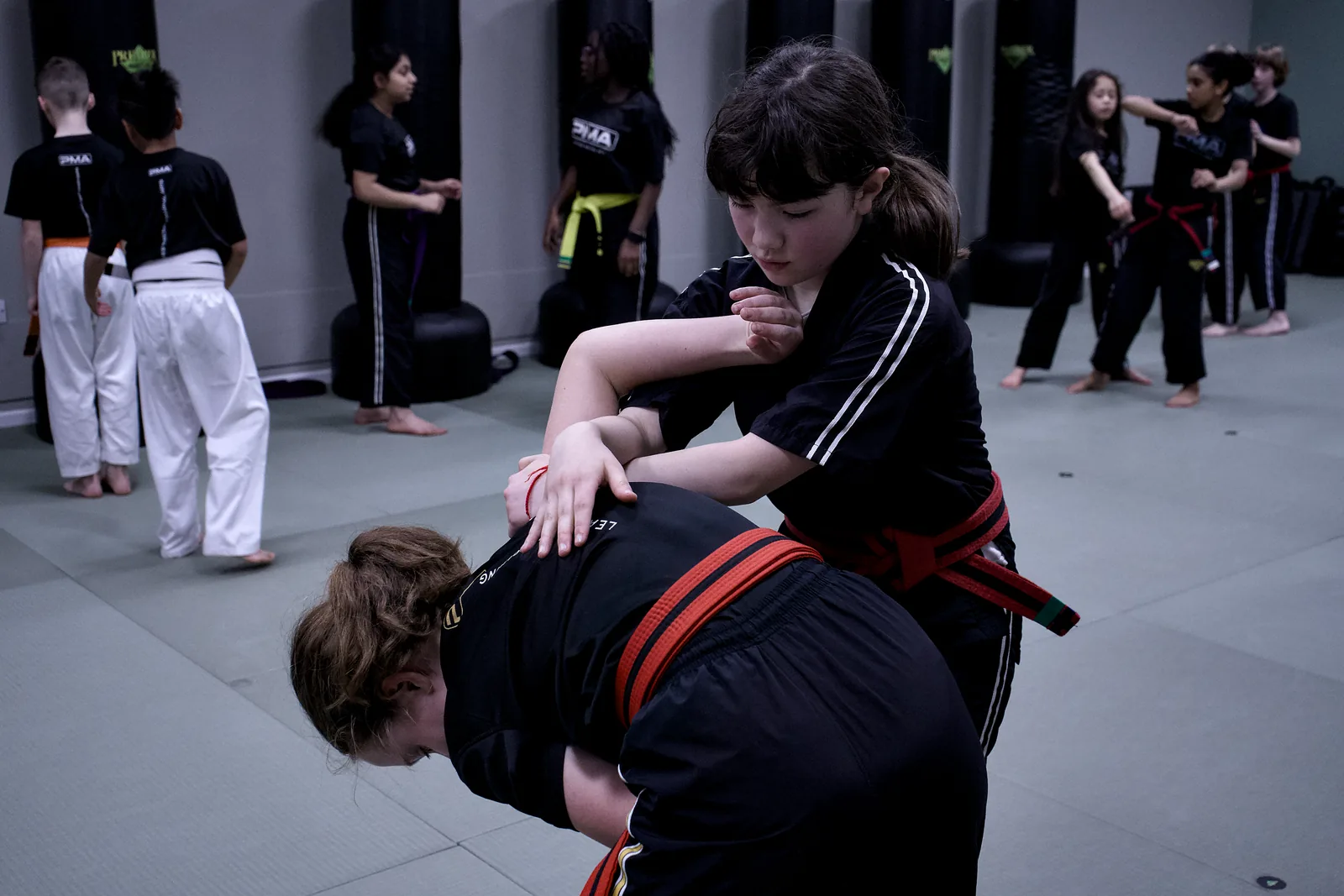 Two children practising a controlled takedown on the mat