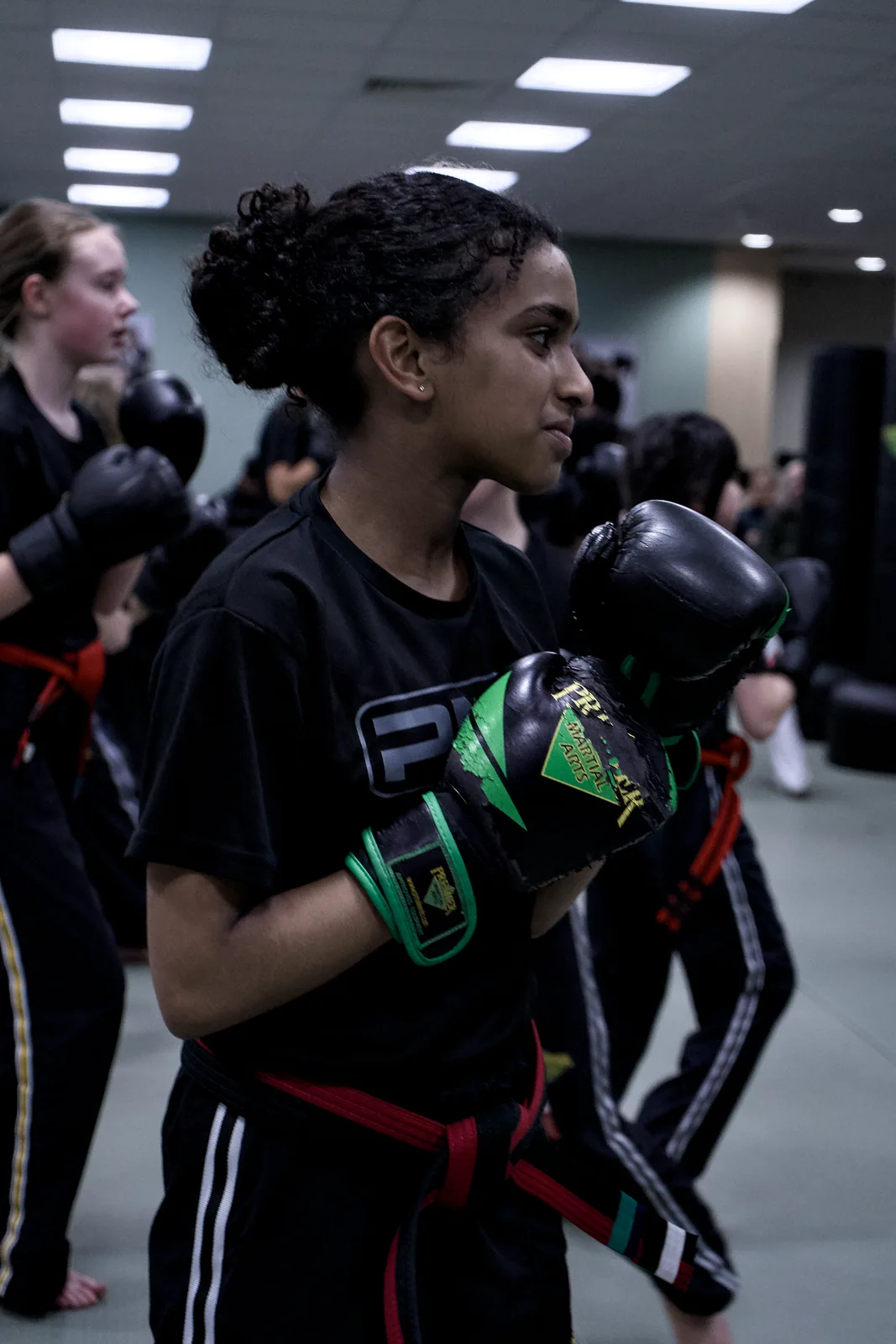 A teenage girl in green gloves holding a boxing guard
