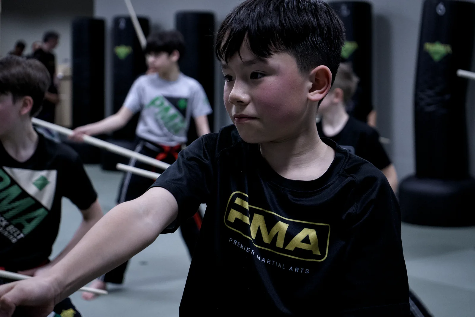 A boy in a red belt working a padded weapon drill with a partner