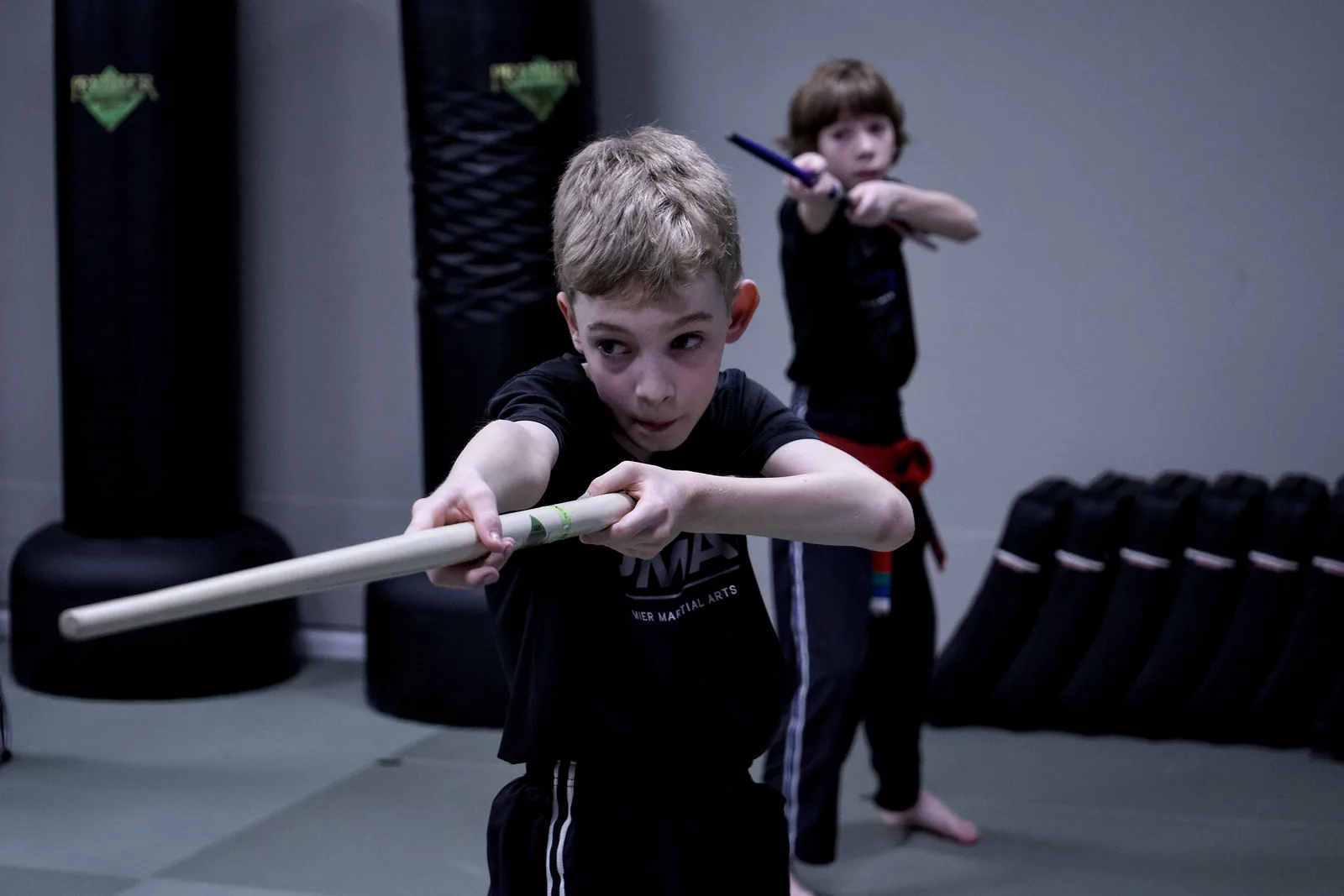 A boy in a red belt extending a training stick in a controlled drill