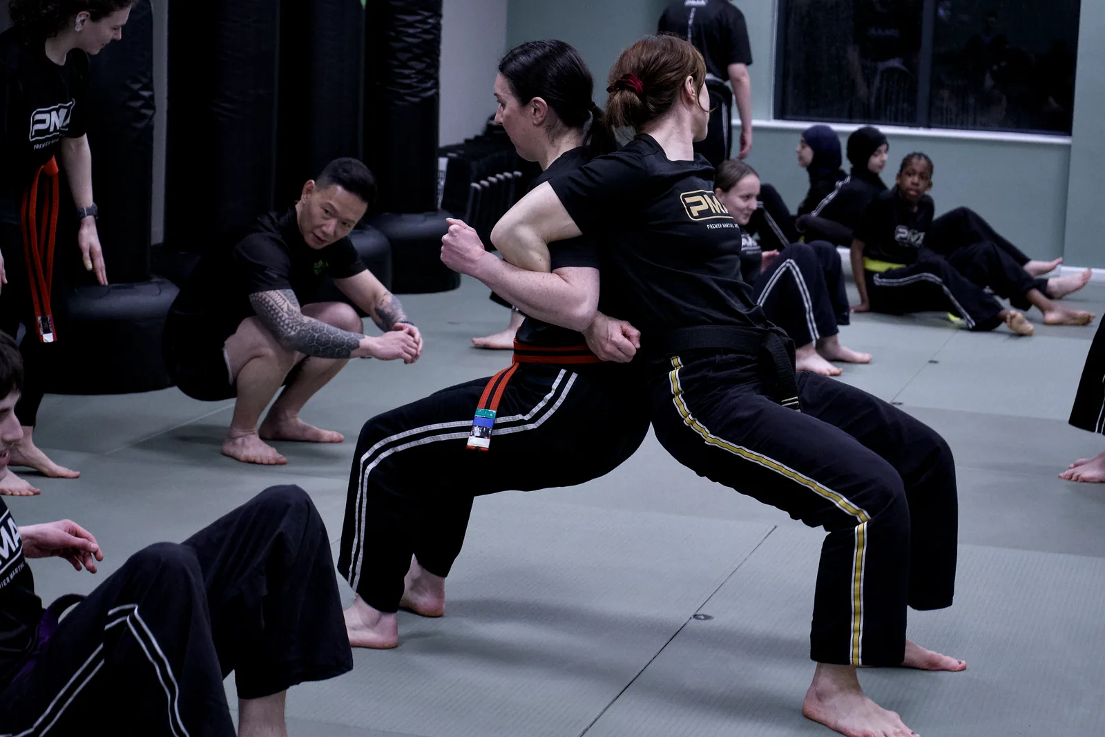 Two adults in fighting stance mid-drill, mirrored across the mat