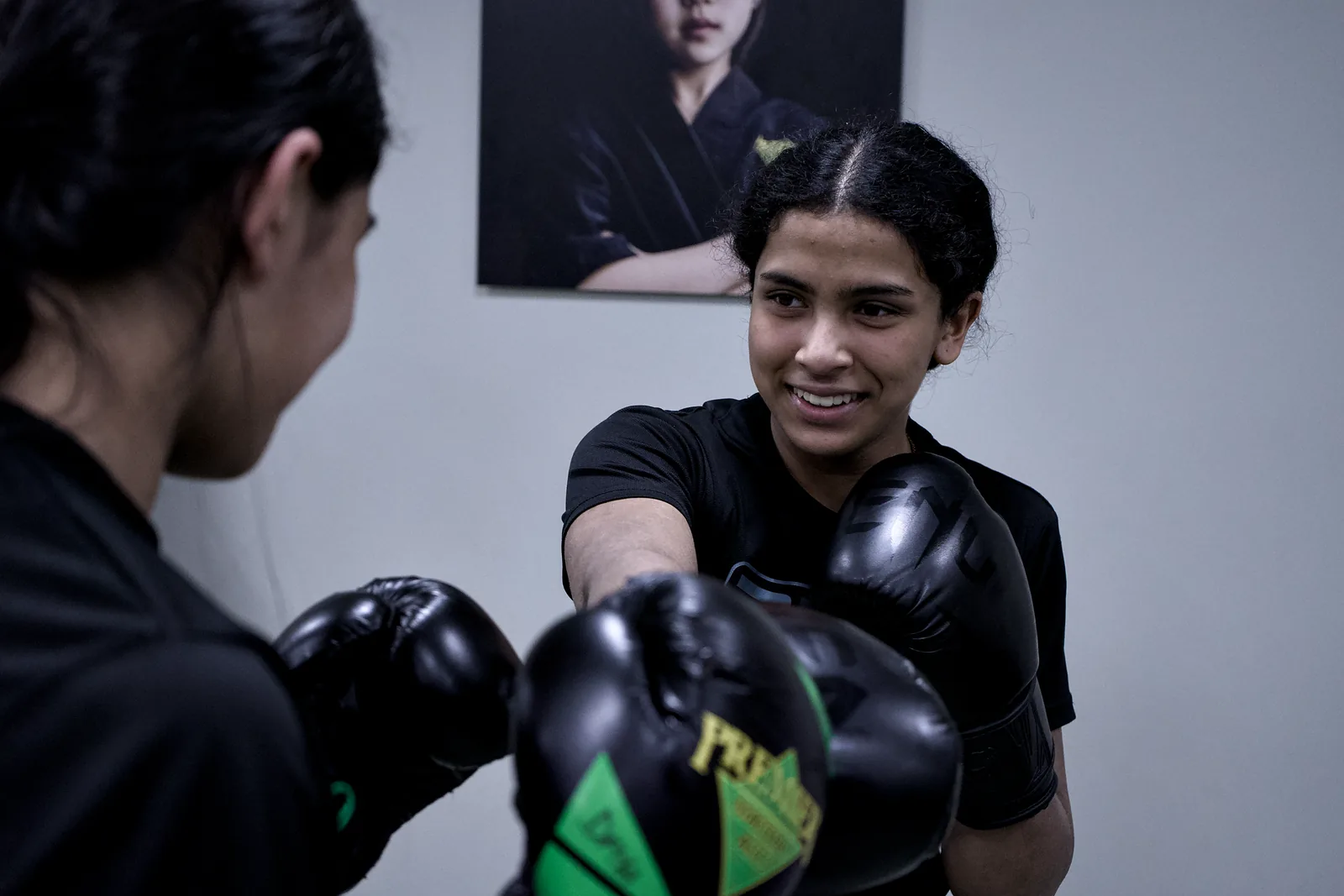 An adult in boxing gloves smiling between rounds on the pads