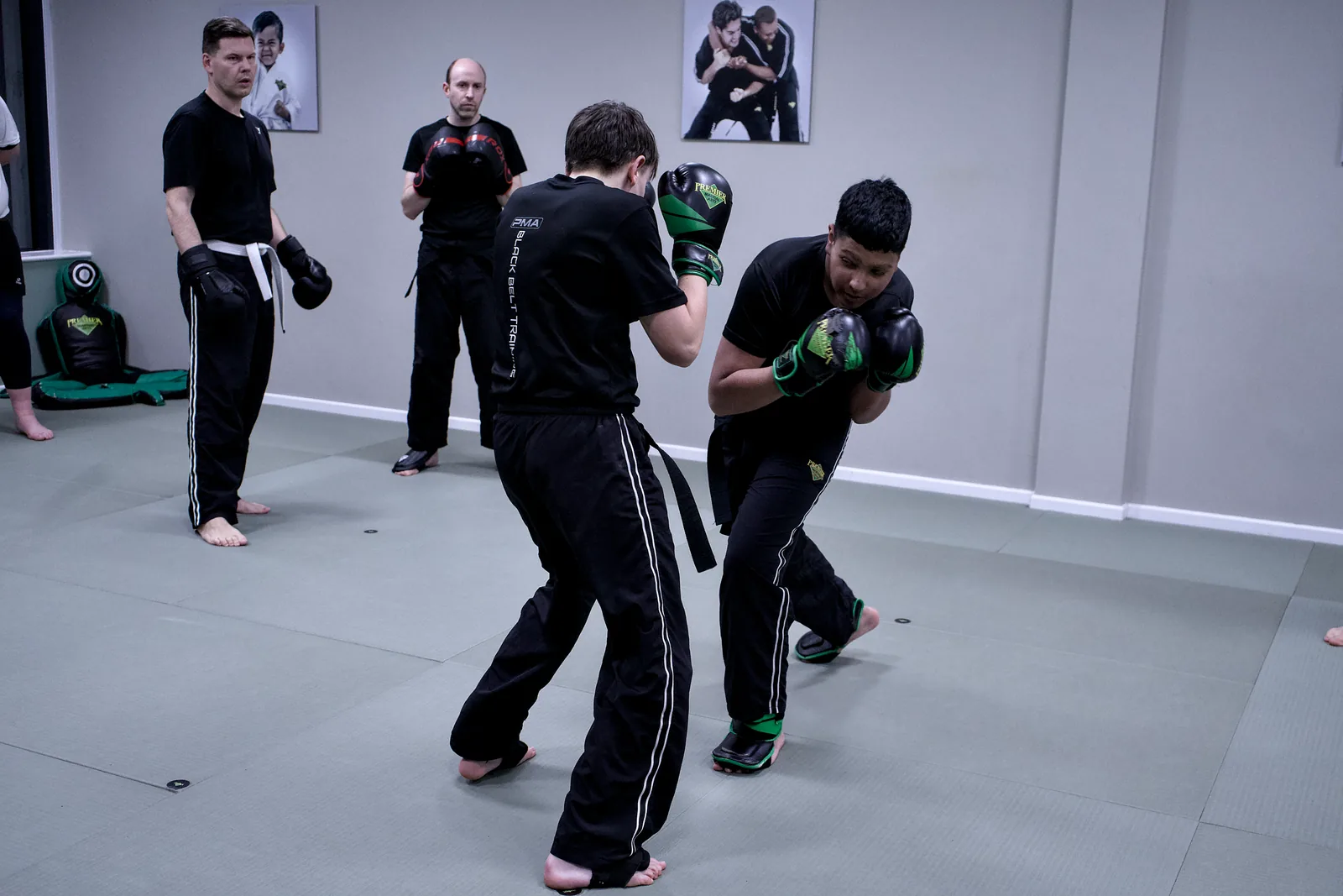 A wide view of the studio with pairs of students working across the mat
