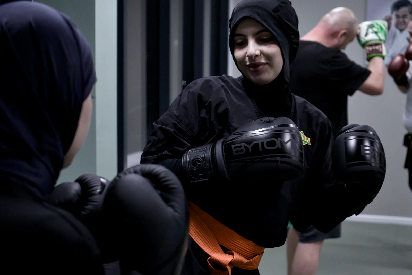 An adult student in gloves working a combination with a partner