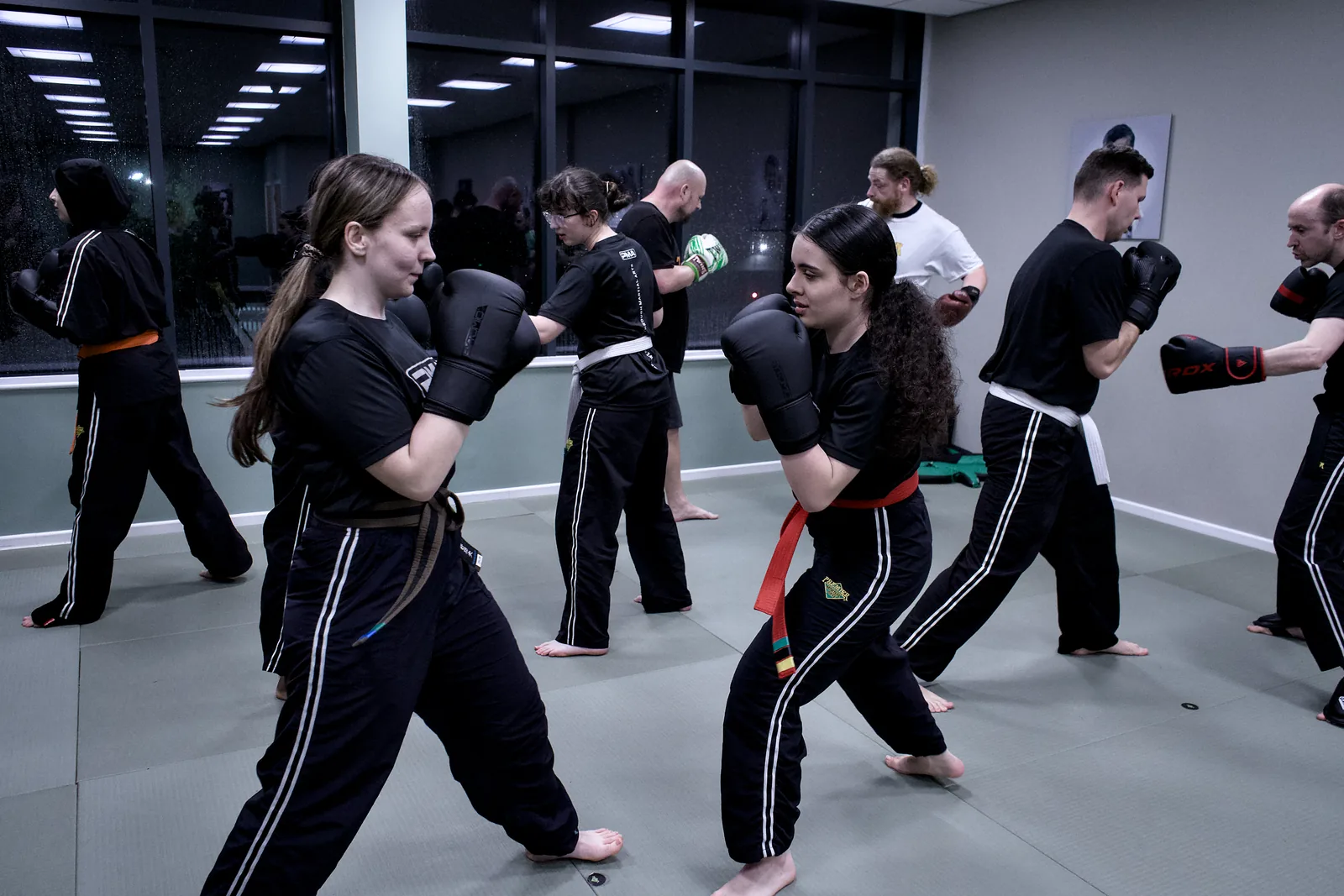 A line of adults drilling combinations across the studio mat