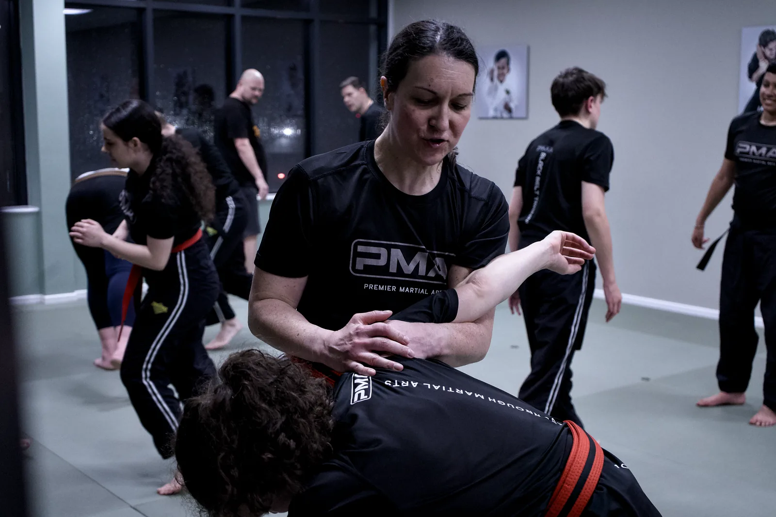 An instructor guiding an adult student through a controlled takedown