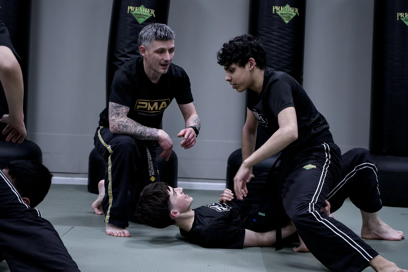 Two adults on the mat working an escape, one guiding the other